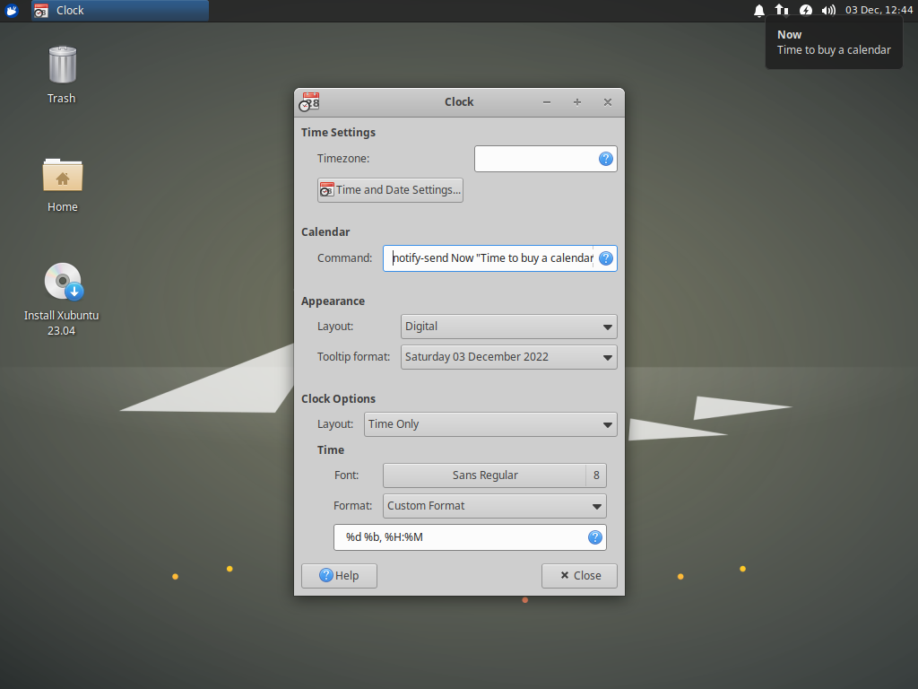 The Xubuntu 23.04 desktop is displayed. The Xfce Panel Clock preferences dialog is open and shows the new Calendar Command setting. The command has been set to show a notification with the message 'Now, Time to buy a calendar'.